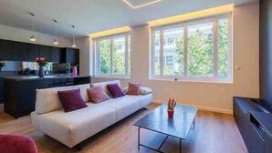 A modern living room with a sofa, a coffee table, and a kitchen area with a dining table.