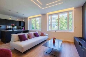 Un saló modern amb un sofà, una taula de centre i una zona cuina amb taula de dinar.