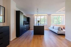 Una cocina moderna con una isla central, un sofá y un televisor.