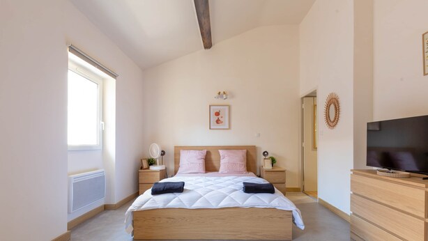 Ein Schlafzimmer mit Bett, Nachttischen, Fernseher und Kommode.