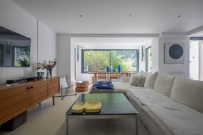 Ein modernes Wohnzimmer mit einer Couch, einem Couchtisch, einem Holzschrank und einem Fernseher.