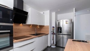 Eine moderne Küche mit eingebautem Ofen, Mikrowelle, Edelstahlkühlschrank und einer Holzarbeitsplatte.
