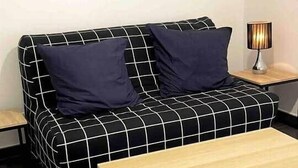Ein modernes Wohnzimmer mit einem schwarz-weißen Karosobasofa, einem Holztisch und einem Stadtbild an der Wand.