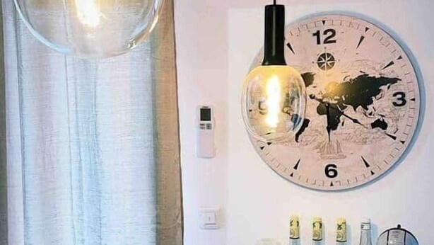 Ein Holztisch mit einer Obstschale, Flaschen und einer Wanduhr.