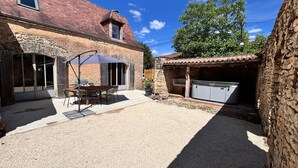 A stone building with a patio, outdoor seating, and a hot tub. - Charming gite with spa in the heart of the Périgord Noir. Ideal for families. (Campagne)