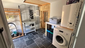 A compact laundry area with a washing machine, drying rack, and storage bins. - Charming gite with spa in the heart of the Périgord Noir. Ideal for families. (Campagne)