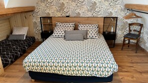 Quarto com uma cama grande, duas mesas de cabeceira, uma cadeira e cabeceira de madeira.