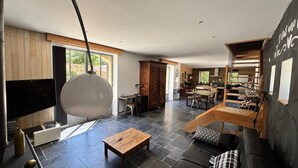 A modern living room with a TV, wooden furniture, and a dining area. - Charming gite with spa in the heart of the Périgord Noir. Ideal for families. (Campagne)