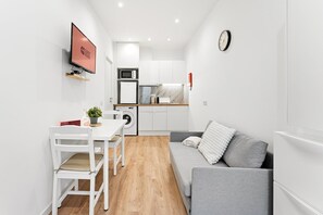 A compact living space with a kitchenette, a dining area, and a seating area. - GuestReady - Miriam's Place (Campanhã)