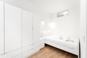 Ein helles Schlafzimmer mit Bett, Kleiderschrank und Spiegel.