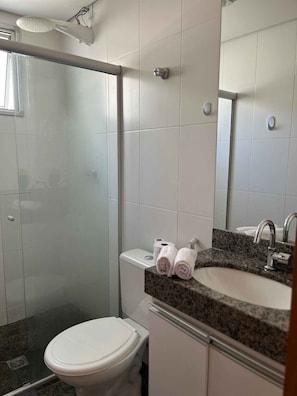 Un baño con ducha, inodoro, lavamanos y espejo.