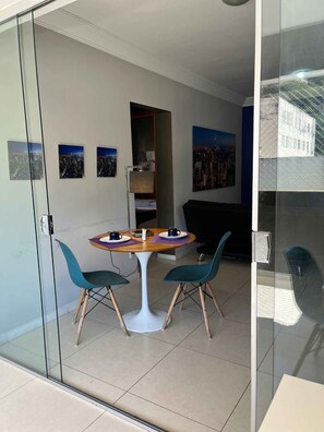 A modern room with a glass partition, a round table with chairs, and cityscape artwork on the walls. - LK Santo Antônio 1 (Belo Horizonte)