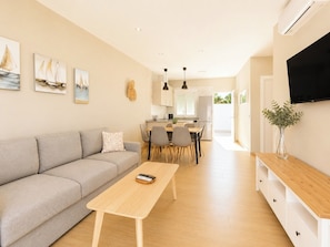A modern living room with a sofa, a coffee table, and a dining area with chairs and a table. - Essence Chiclana 1 . (Chiclana de la Frontera)