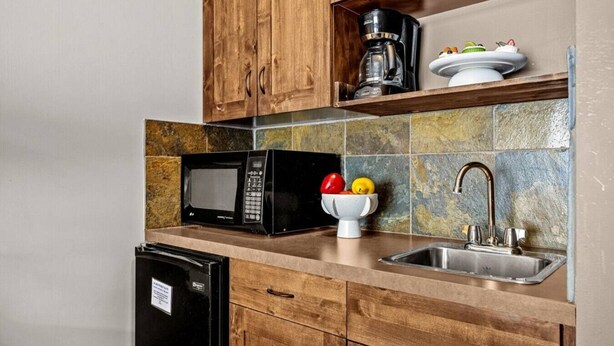 A kitchen with wooden cabinets, a microwave, a coffee maker, a fruit bowl, and a sink. - Golden Alpine Hideaway Studio Hot tub + Ski-in/out (Golden)
