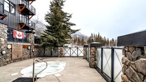 A spa area with a hot tub, stone walls, and a flag. - Golden Alpine Hideaway Studio Hot tub + Ski-in/out (Golden)