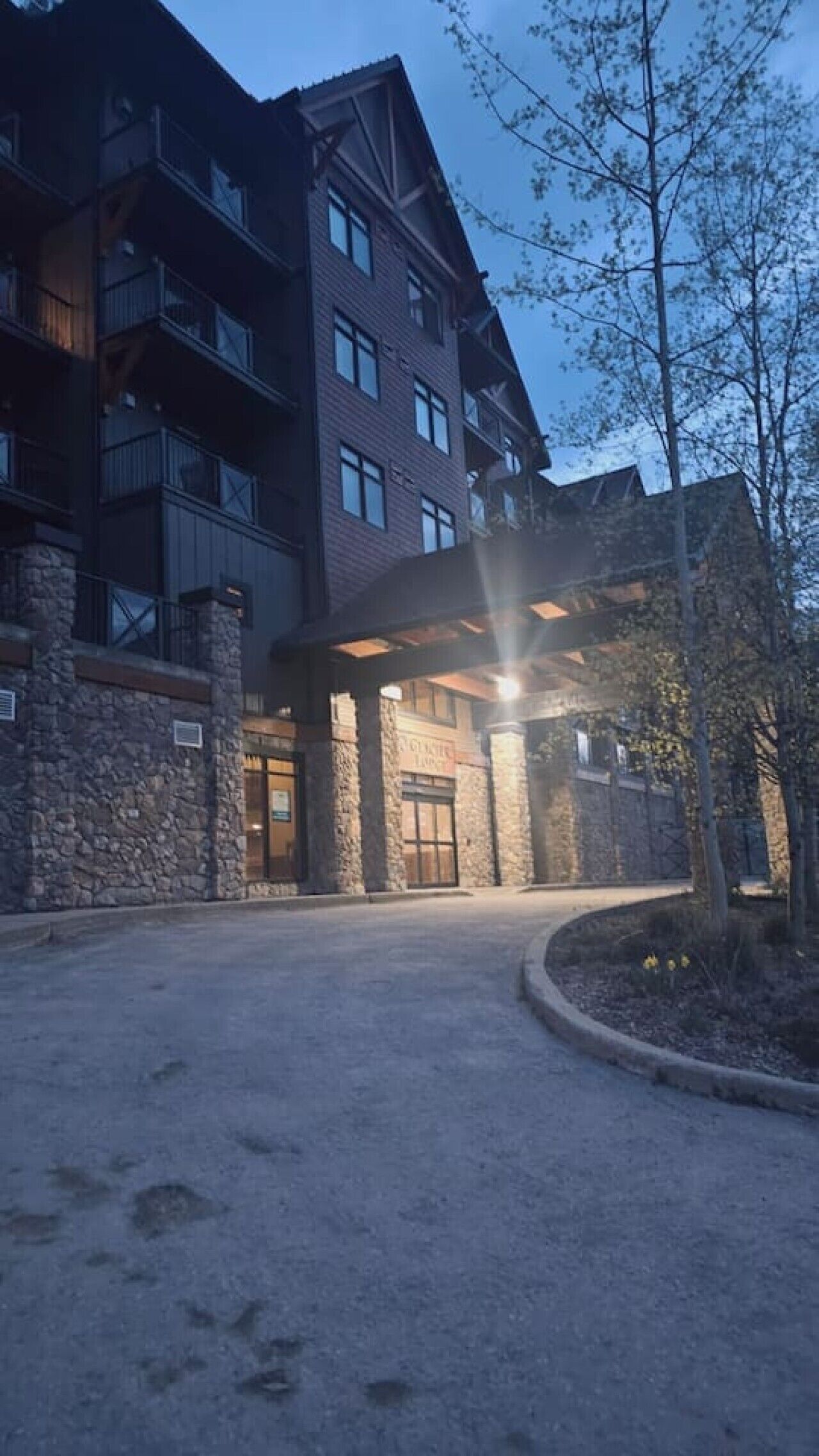 A multi-story building with a stone facade, a covered entrance, and a clear sky.