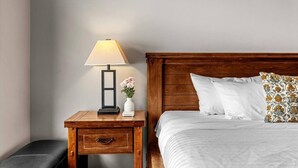 A neatly made bed with white linens, a wooden headboard, and a patterned pillow. - Golden Alpine Hideaway Studio Hot tub + Ski-in/out (Golden)