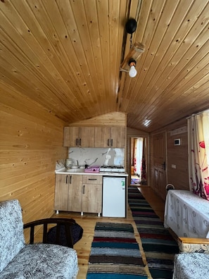 Un interior de madera con una zona de cocina, una mesa de comedor y un sofá.