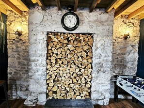 Ein rustikales Interieur mit einer Steinwand, einer Holzbalkendecke, einer Uhr und einem Kicker.