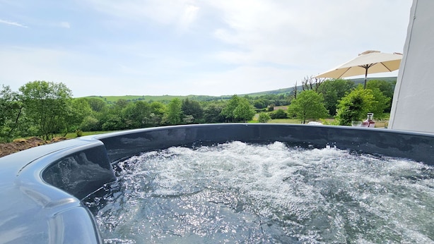 Un jacuzzi con vistas a un paisaje verde y un edificio blanco al fondo.