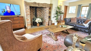 Una sala de estar acogedora con chimenea, un sofá, una mesa de centro y un televisor.