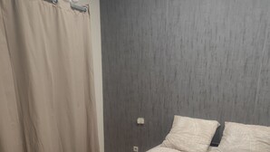 Makuuhuone, jossa on sänky, verhot ja seinään asennettu valokytkin.