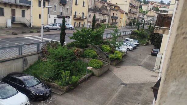 Asuinkatu, jossa on parkkeerattuja autoja, jalankulkijoiden suojatie ja parvekkeellisia rakennuksia.