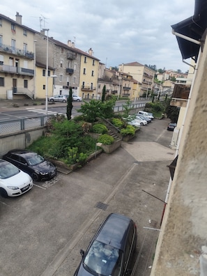 Une rue résidentielle bordée de voitures garées, avec un passage piéton et des immeubles dotés de balcons.