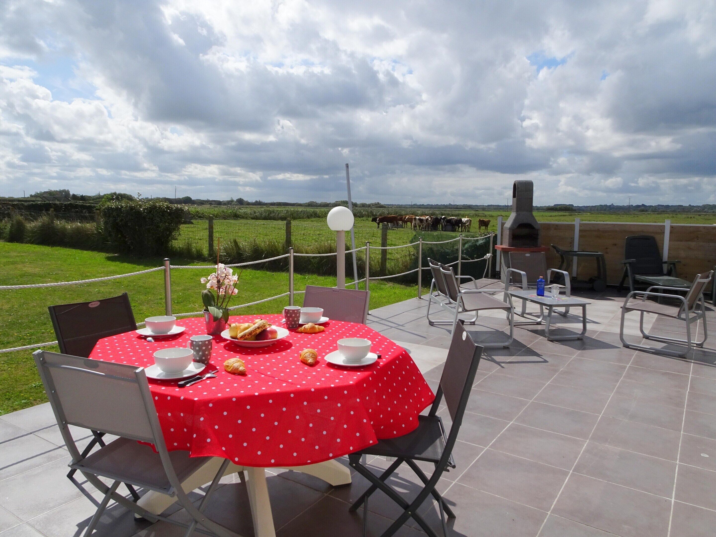 An outdoor dining area with a red tablecloth, chairs, and a pizza oven.