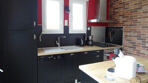 Una cocina moderna con gabinetes negros, una estufa de acero inoxidable y una pared decorativa de ladrillo.