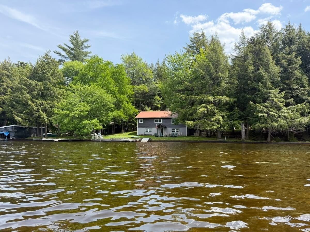 A house by a lake with a dock, surrounded by trees.