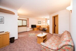 Un espacio habitable compacto con sofá, televisor, comedor y cocina.