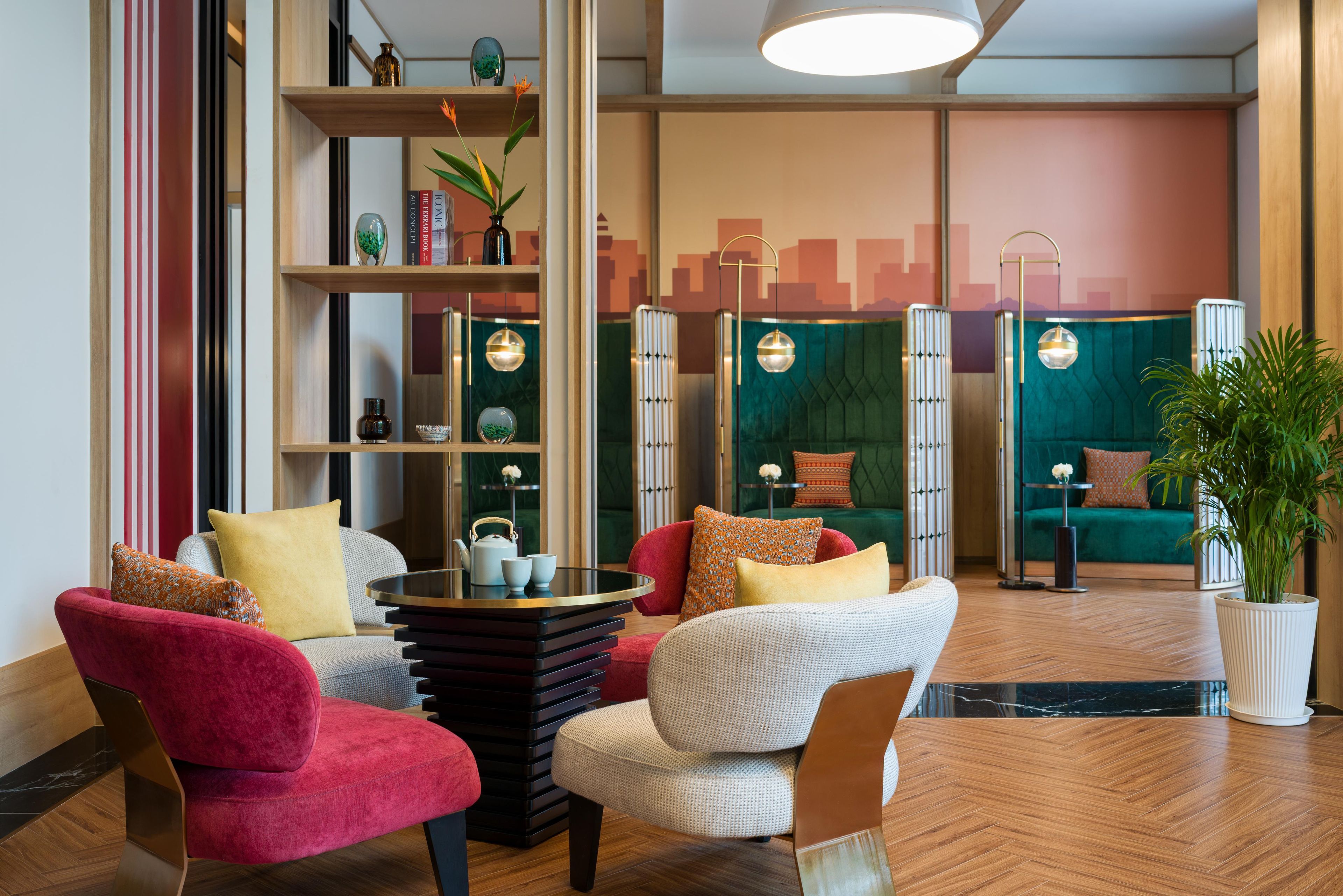 A modern lounge area with a round table, red and white chairs, and a green sofa.