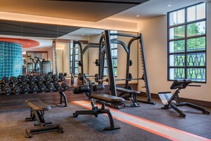 Un gimnasio con equipo de levantamiento de pesas, bancos y mancuernas.
