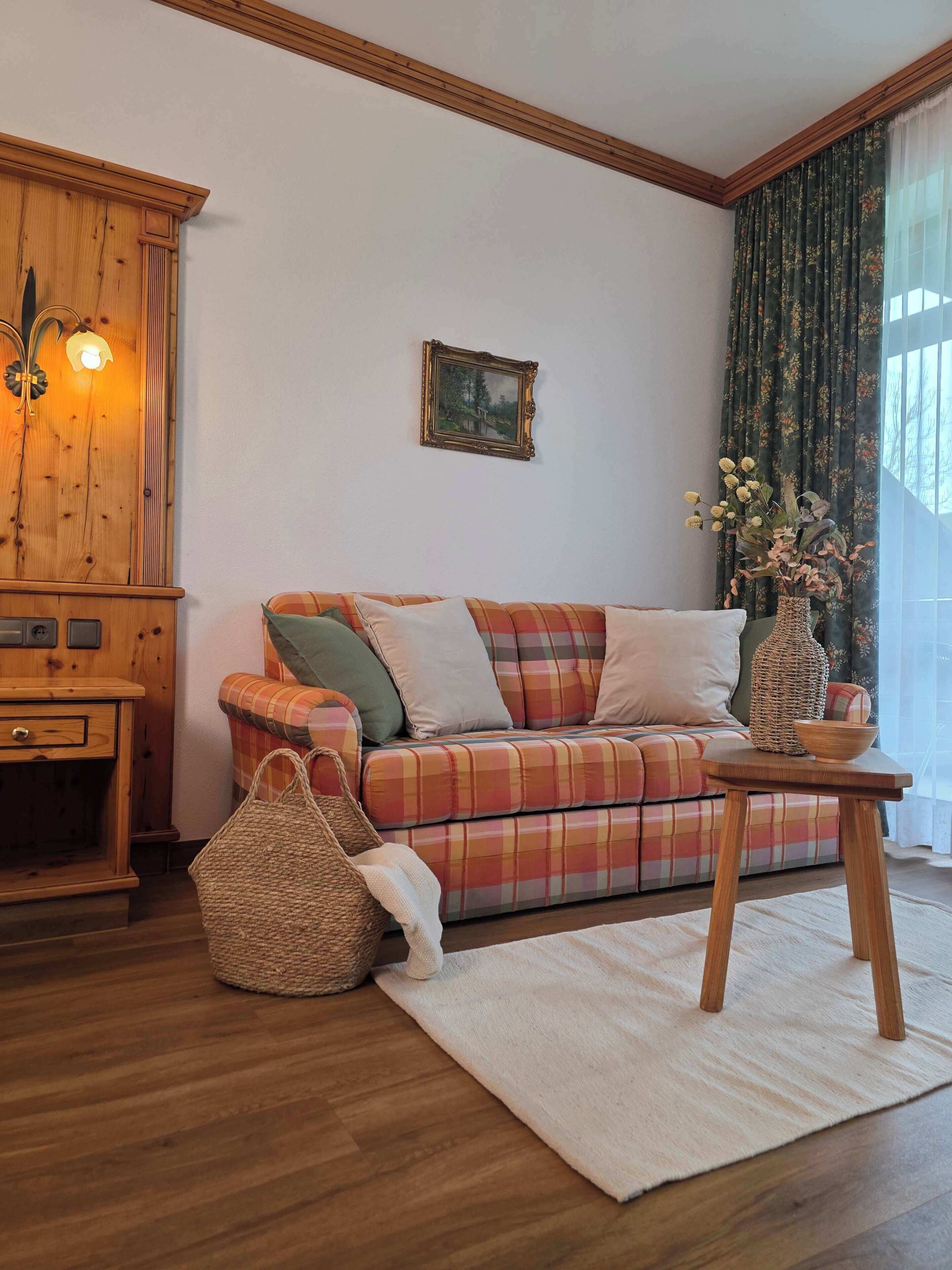 Una sala de estar acogedora con un sofá de cuadros, un mueble de madera y una cesta tejida.