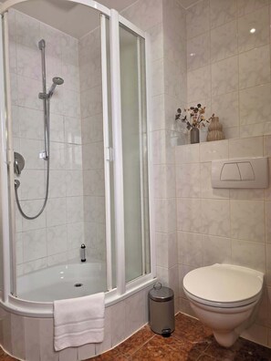 Ein Badezimmer mit einer Duschkabine, einer Badewanne, einer Toilette und einem Mülleimer.