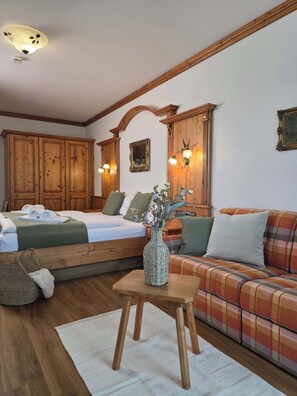Ein Zimmer mit einem Bett, einem Sofa, einem Holztisch mit einer Vase und einer Deckenleuchte.