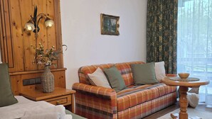 Een hotelkamer met een bed, een bank, een houten kast, een aan de muur hangend schilderij en een raam met gordijnen.