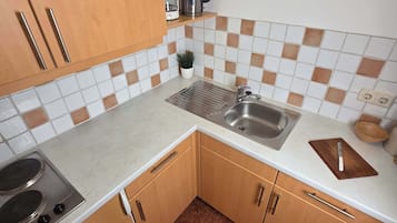 Eine kleine Küche mit Herd, Spüle und Holzschränken.
