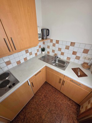 Una cocina compacta con estufa, lavamanos y armarios de madera.
