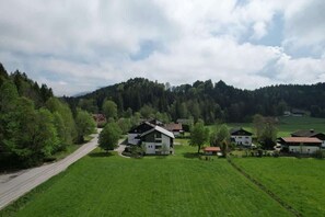 Ein ländliches Dorf mit Häusern, umgeben von grünen Feldern und einem bewaldeten Hügel.