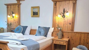 Una cama con estructura de madera, cabecera, una mesita de noche con lámpara y un cuadro colgado en la pared.