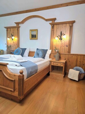 Ein Bett mit Holzrahmen und Kopfteil, ein Nachttisch mit Lampe sowie ein an der Wand hängendes Bild.