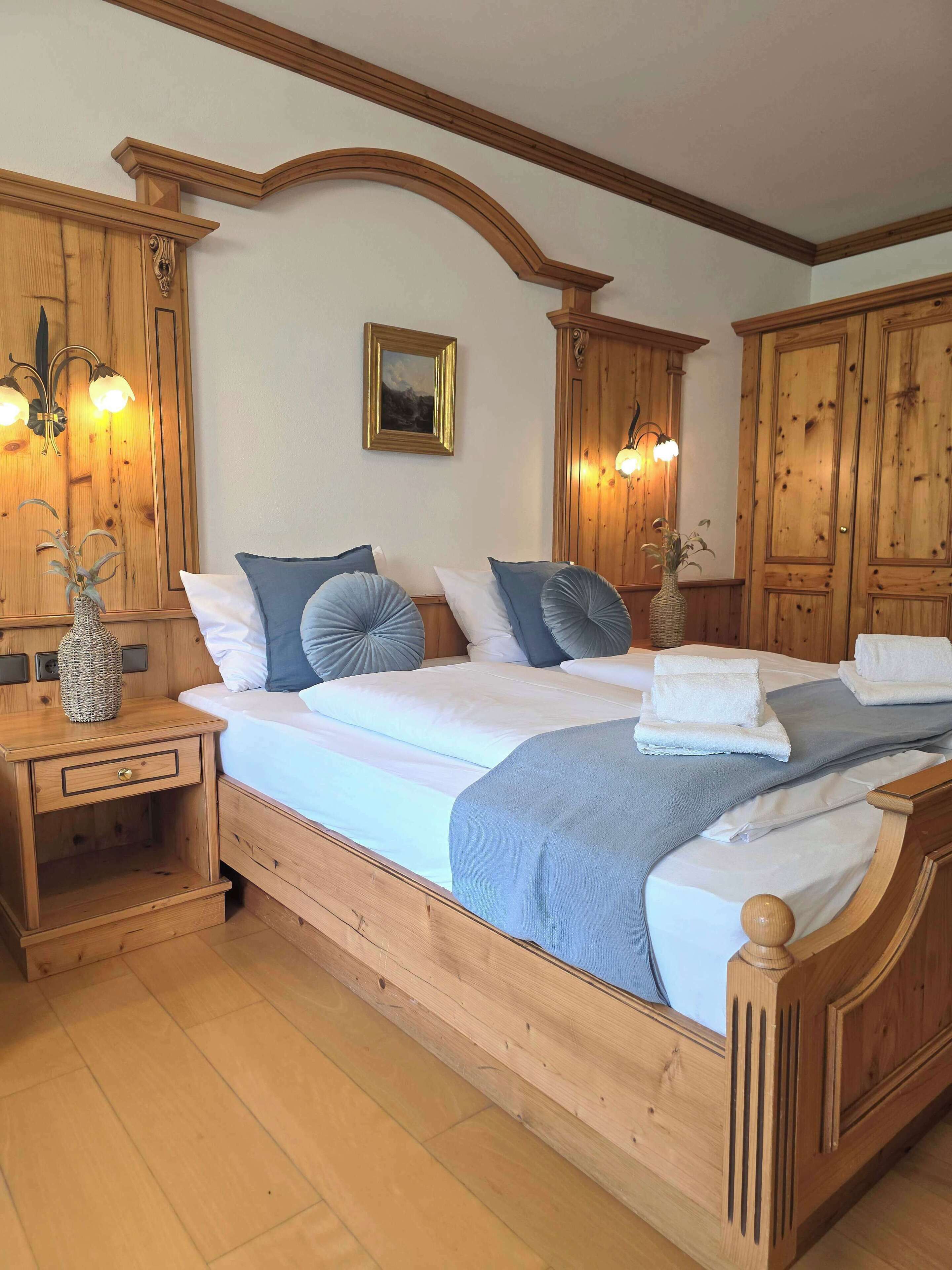Ein Bett mit Holzrahmen, einem Kopfteil, zwei Nachttischen und einem Wandbild.