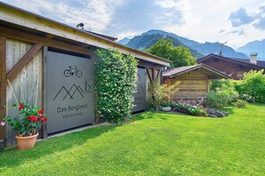 Un edificio con un cartello che riporta la scritta 'Das Bergland Vital & Activity', circondato da un prato curato e con le montagne sullo sfondo.