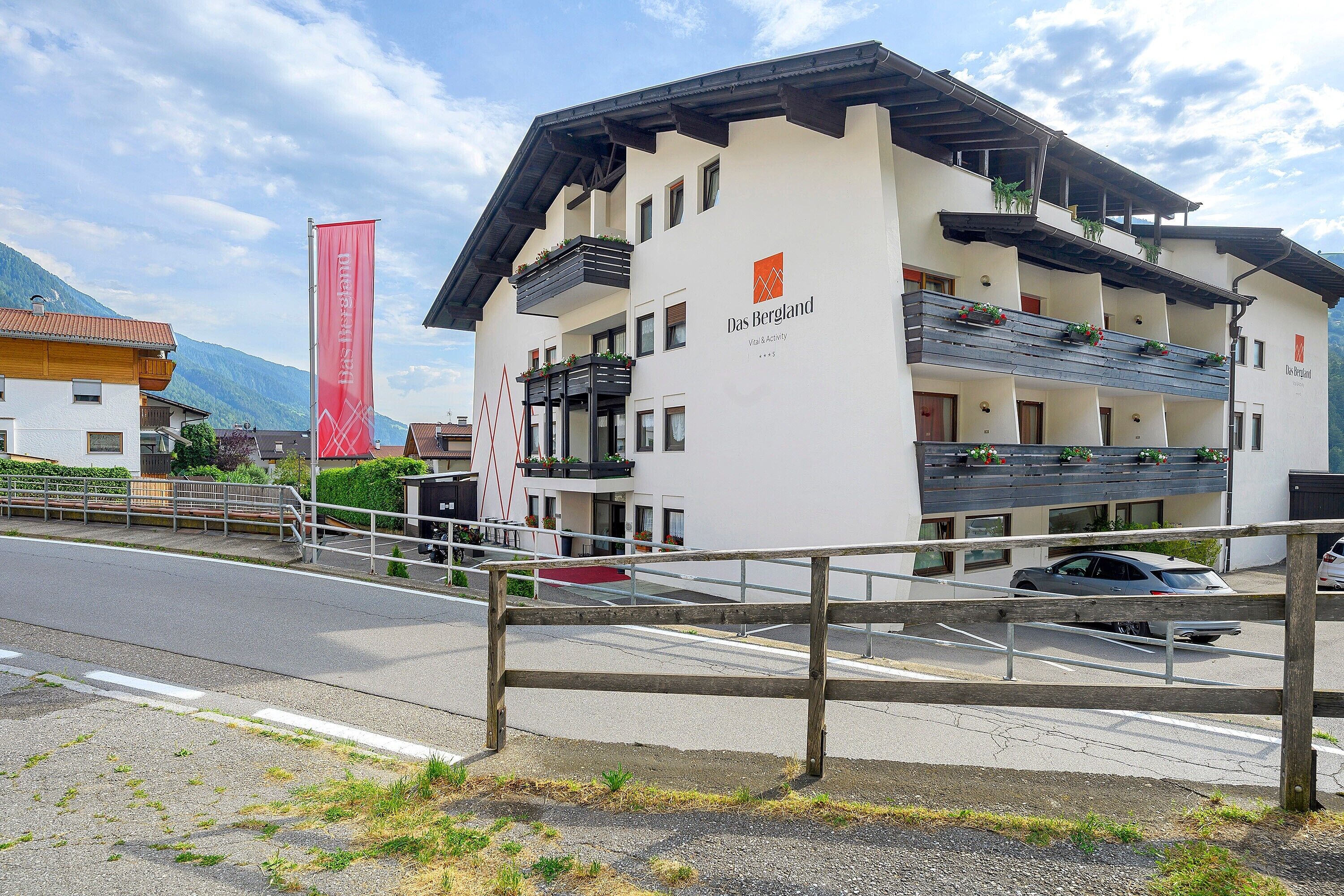 A building with balconies, a red banner, and a mountain in the background.