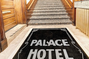 A hotel entrance with a carpeted staircase leading to a door with a wooden frame.