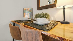 A dining area with a wooden table, two chairs, a lamp, a potted plant, and a framed picture on the wall. - Downtown Palace Hotel Suite - Steps to Adventure (Salida)