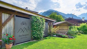 A building with a sign reading 'Das Bergland Vital & Activity' and a bicycle symbol, surrounded by a well-maintained lawn and mountains in the background. - Spacious Timmels Suite with South Balcony and Free Wellness & Pool Access (St. Leonhard in Passeier)