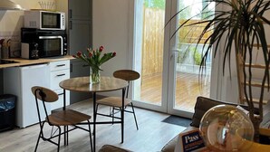 Une cuisine moderne dotée d’appareils électroménagers intégrés, un coin repas avec une table et des chaises, et une grande porte-fenêtre coulissante donnant sur un patio extérieur.